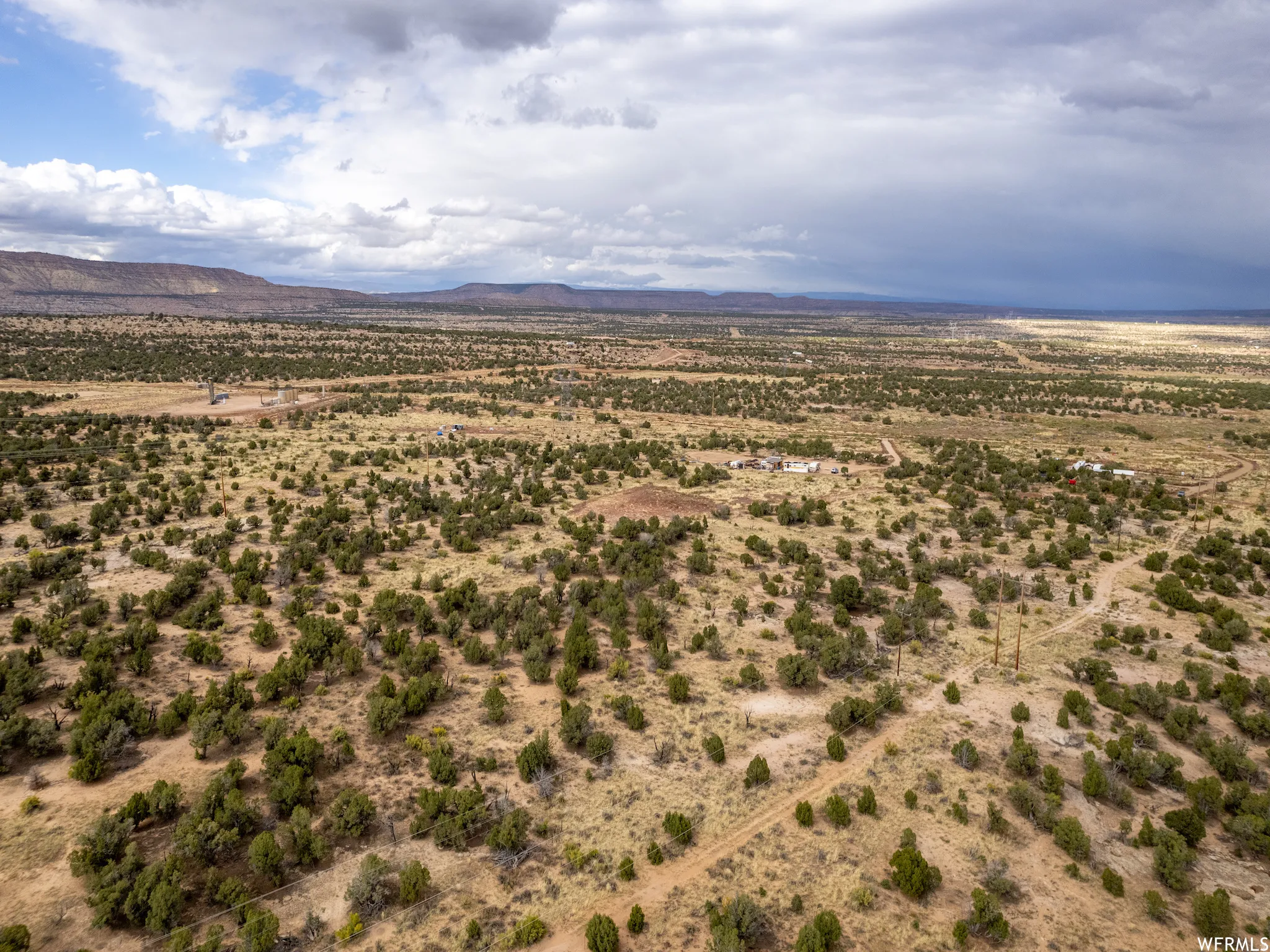 Expansive desert landscape with scattered green scrub and distant mountain ranges