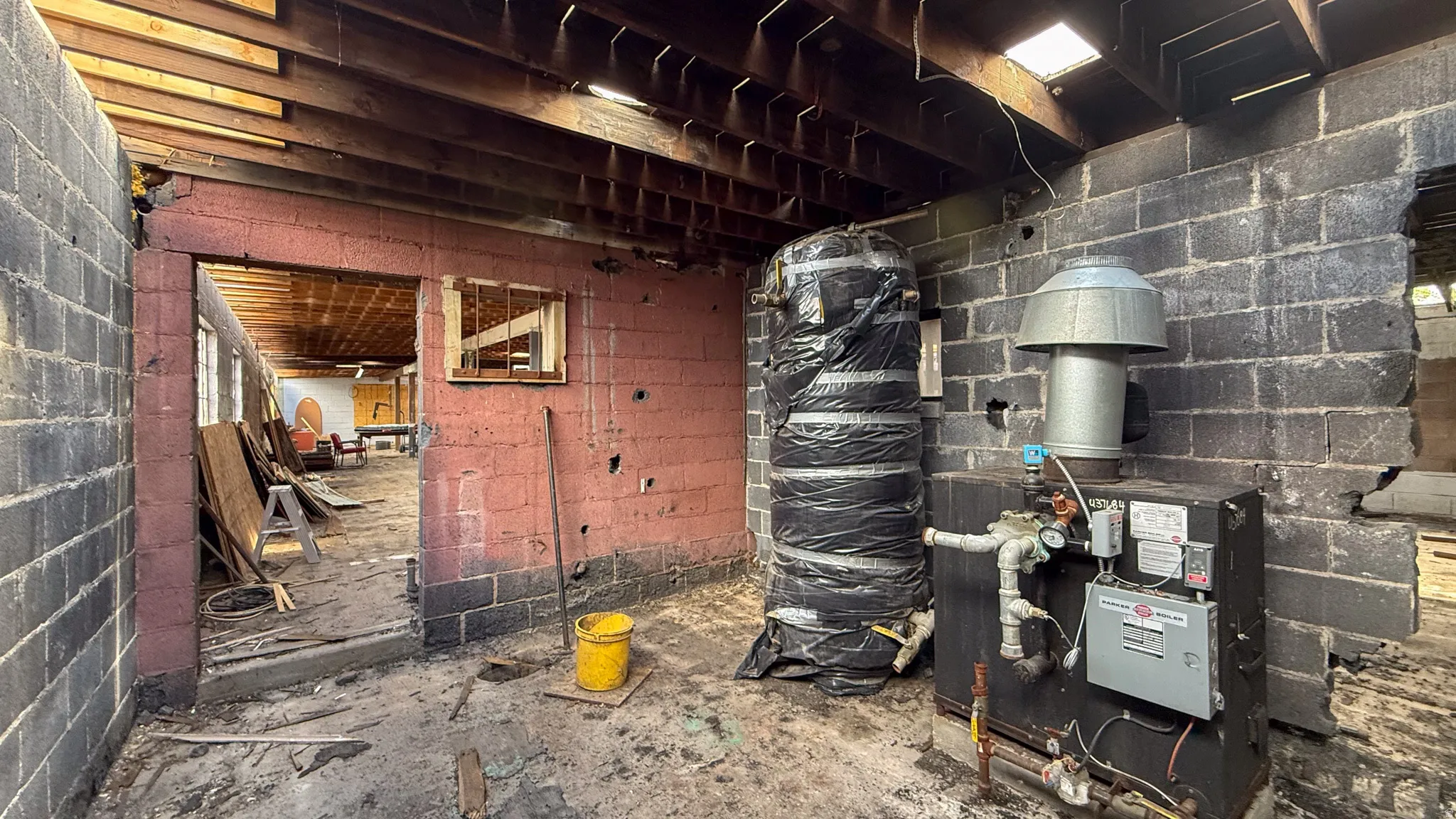Exposed ceiling joists and block walls define this interior space, featuring a large boiler system with an insulated tank
