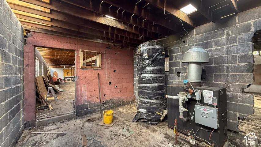 Exposed ceiling joists and block walls define this interior space, featuring a large boiler system with an insulated tank