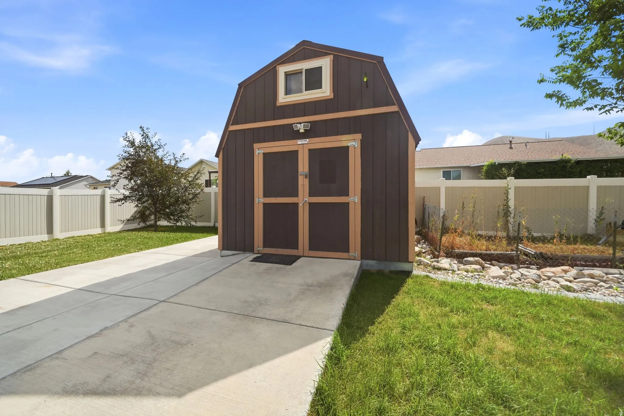 Freestanding barn-style shed featuring double doors, an upper-level window, and a concrete approach