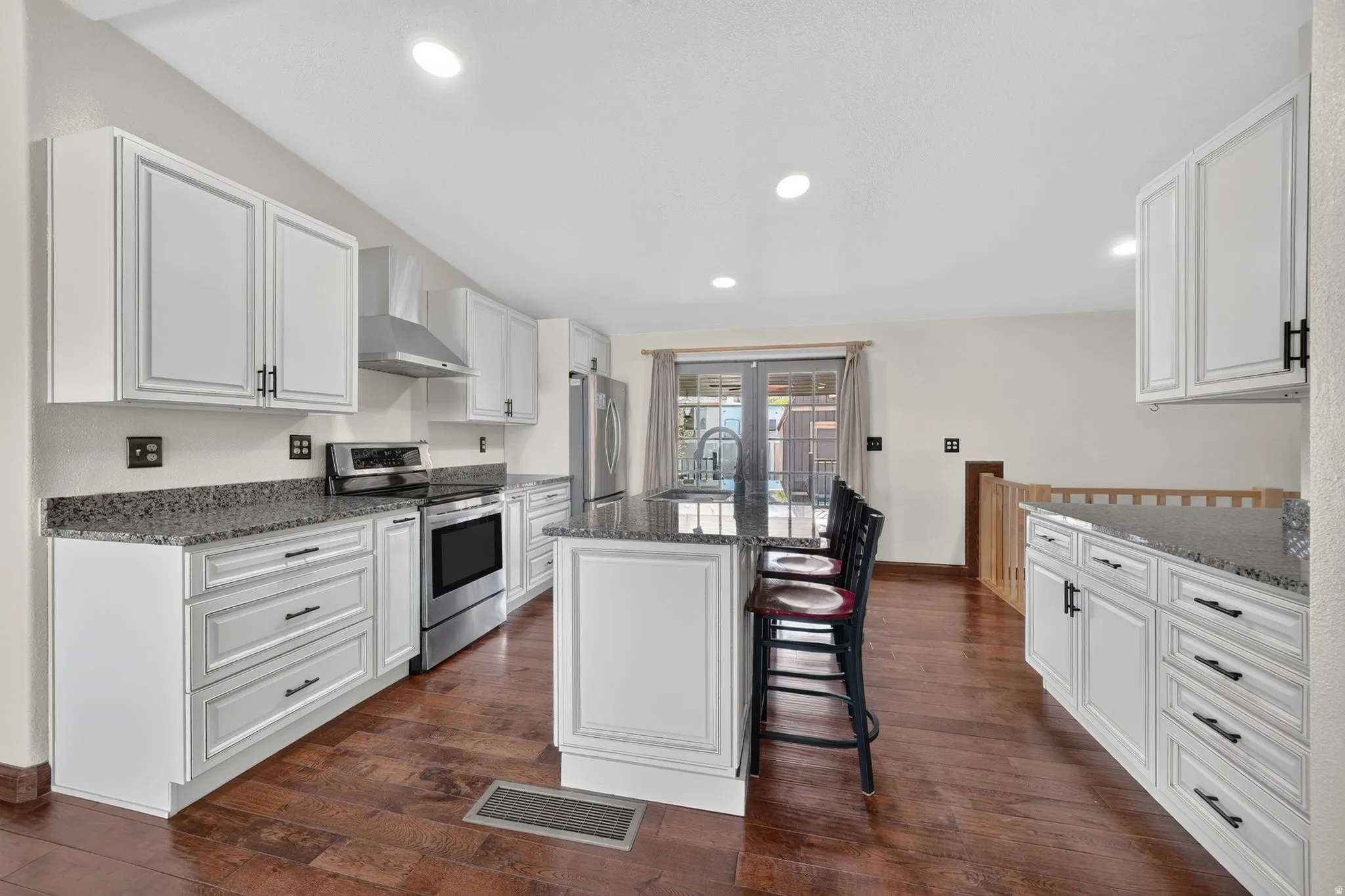 Kitchen with white cabinetry, dark hardware, and granite countertops