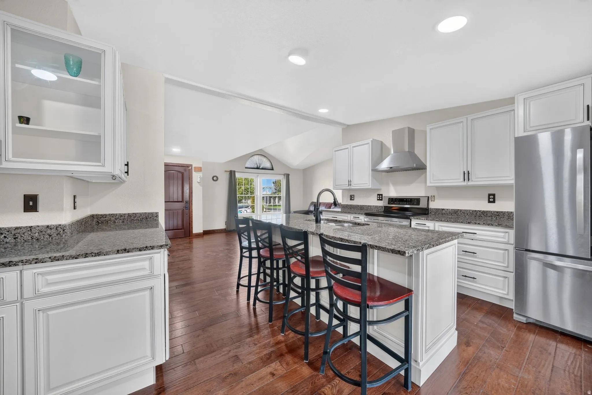 Kitchen featuring white cabinetry, stainless steel appliances, a center island with seating, dark wood-finish flooring, and recessed lighting