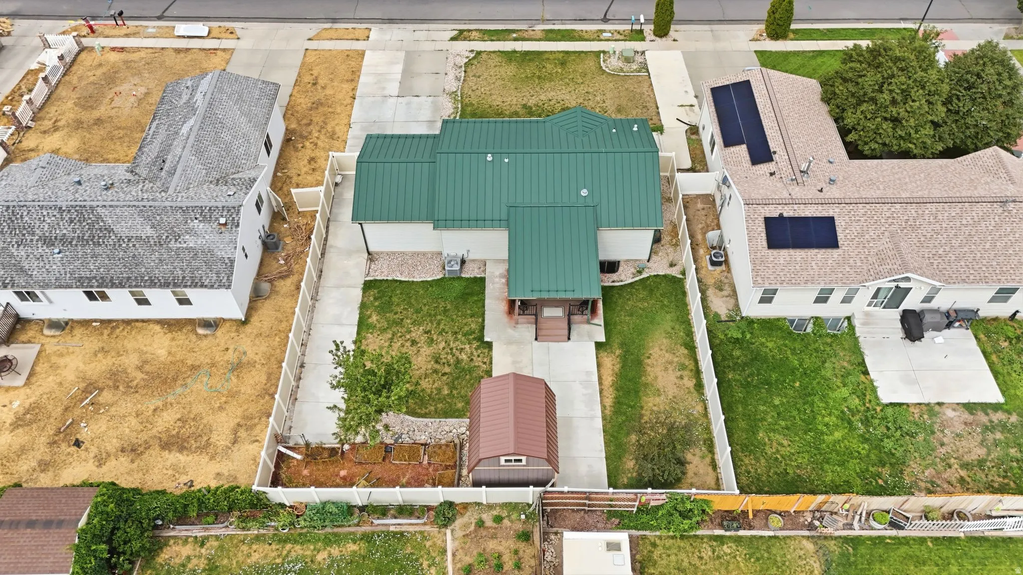 Property featuring a green metal roof, light-colored exterior siding, and a fenced perimeter