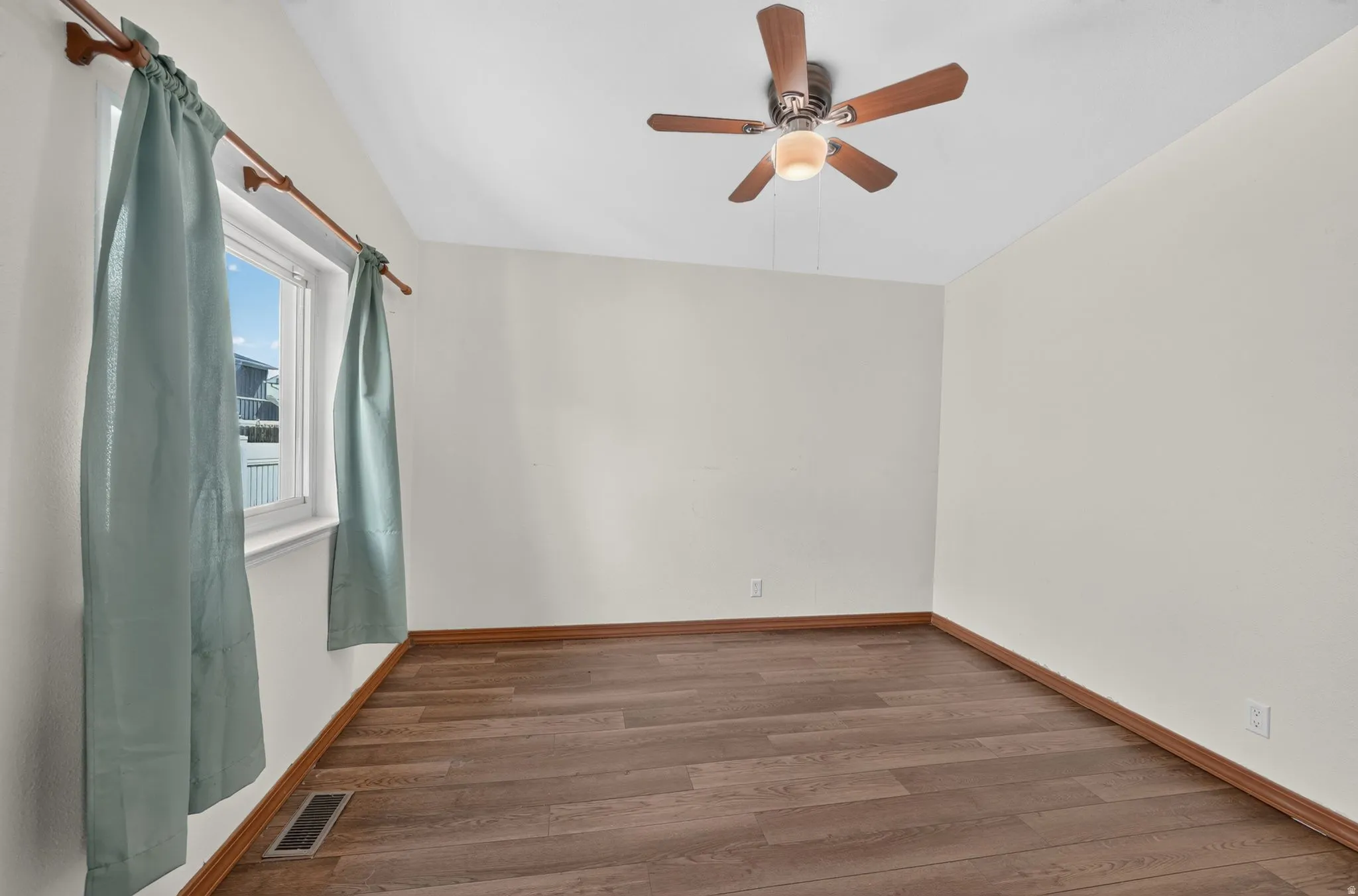 Room with wood-finish flooring, light-toned walls, and a ceiling fan with integrated lighting