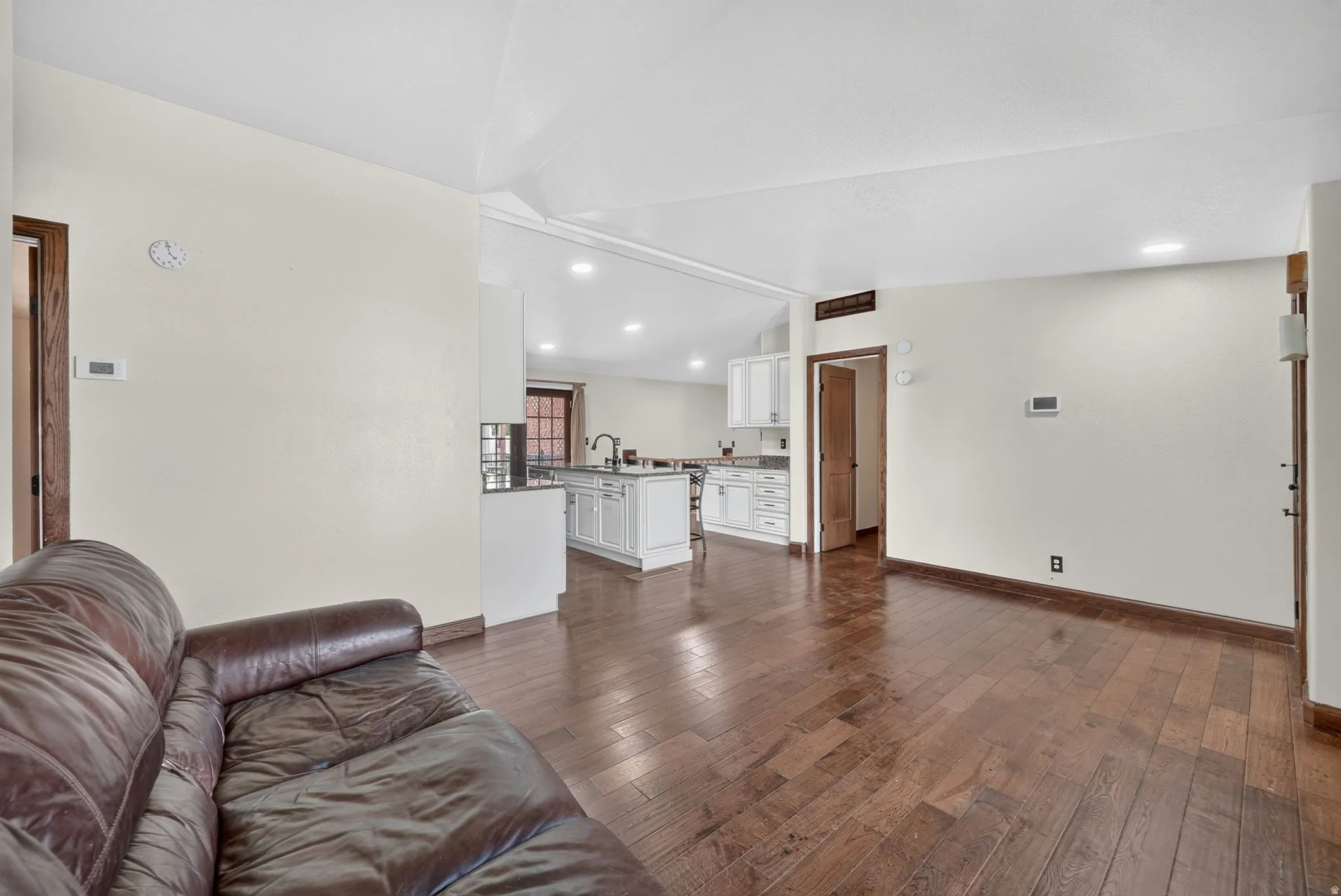 Open-concept living space featuring wood-finish flooring, recessed lighting, and a white color palette