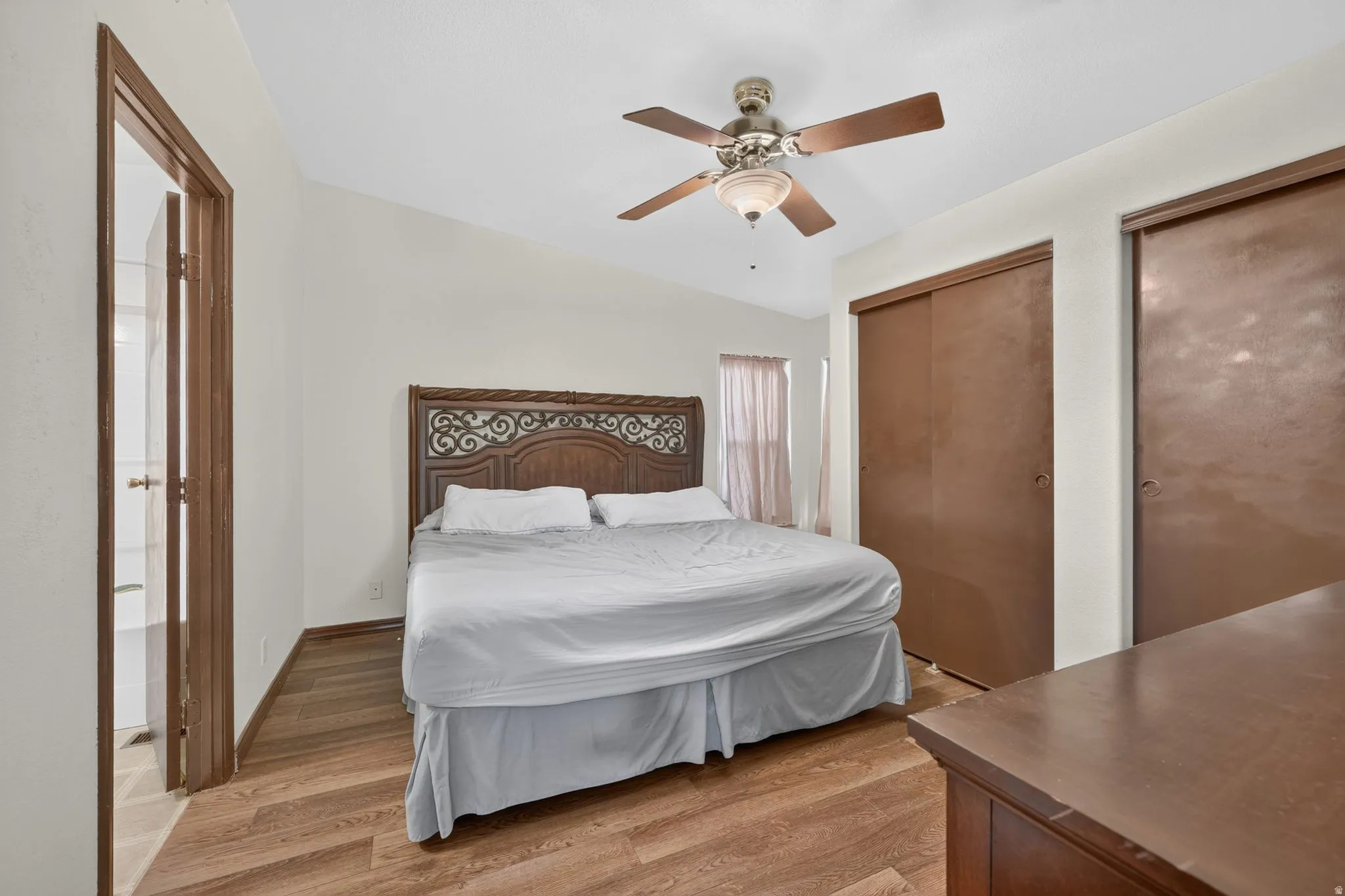 Bedroom featuring wood-finish flooring, a ceiling fan with integrated lighting, a vaulted ceiling, and sliding closet doors