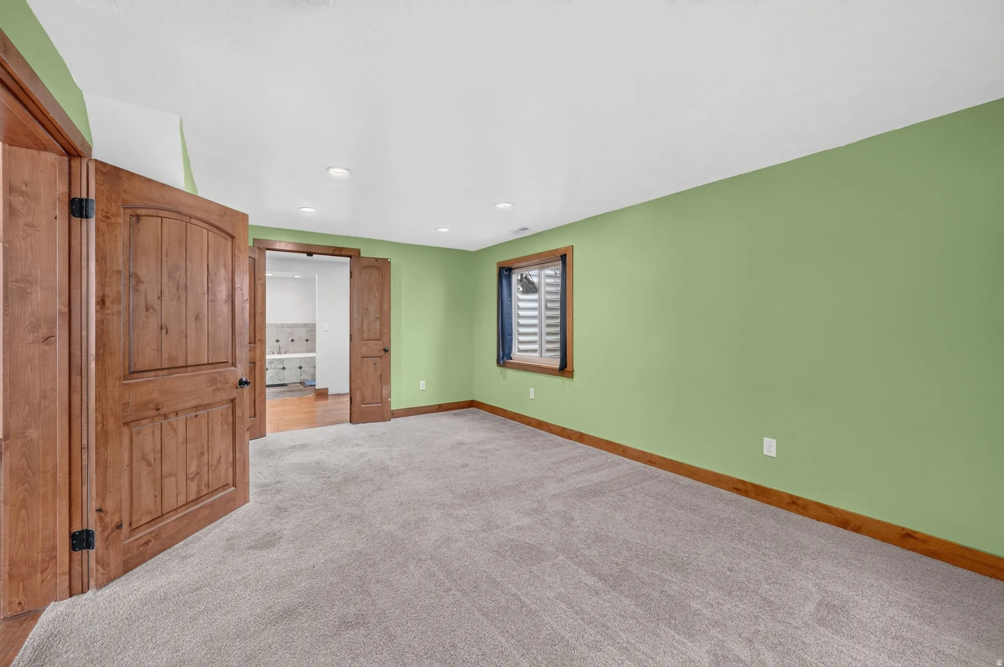 Spacious room featuring light green walls and plush gray carpeting