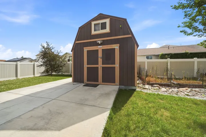 Freestanding barn-style shed featuring double doors, an upper-level window, and a concrete approach