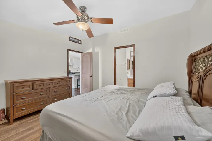 Spacious room featuring wood-finish flooring, light neutral walls, and a ceiling fan with integrated lighting