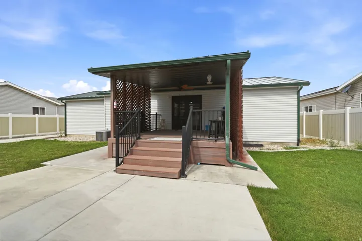 Rear exterior featuring a covered porch with lattice-work privacy screens, wood-finish decking, and black metal railings