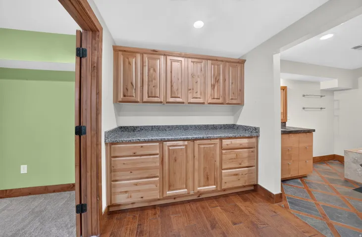 Cabinetry featuring natural wood-finish, granite-style countertops, and recessed lighting