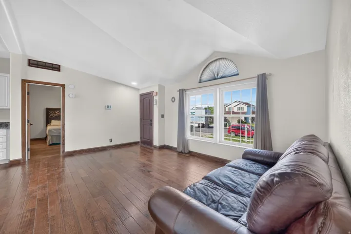 Living area featuring vaulted ceilings, wood-finish flooring, and a large window with an arched transom