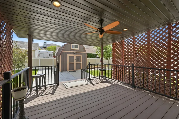 Expansive covered deck featuring a ceiling fan with light, recessed lighting, and wood-finish decking