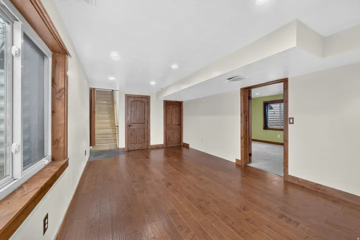 Spacious room featuring rich wood-finish flooring, recessed lighting, and crisp white walls