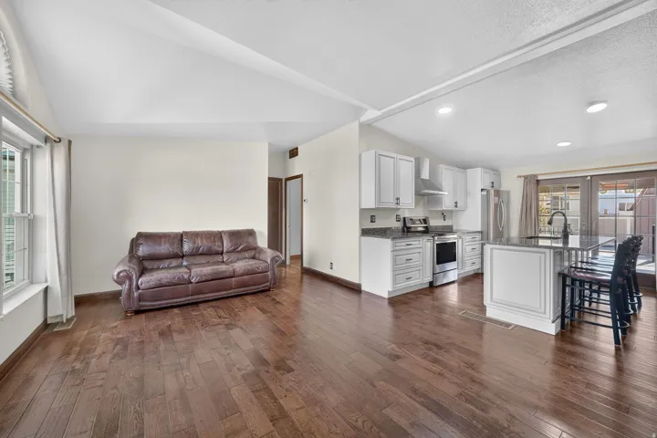 Open-concept living space featuring wood-finish flooring, white walls, and vaulted ceilings