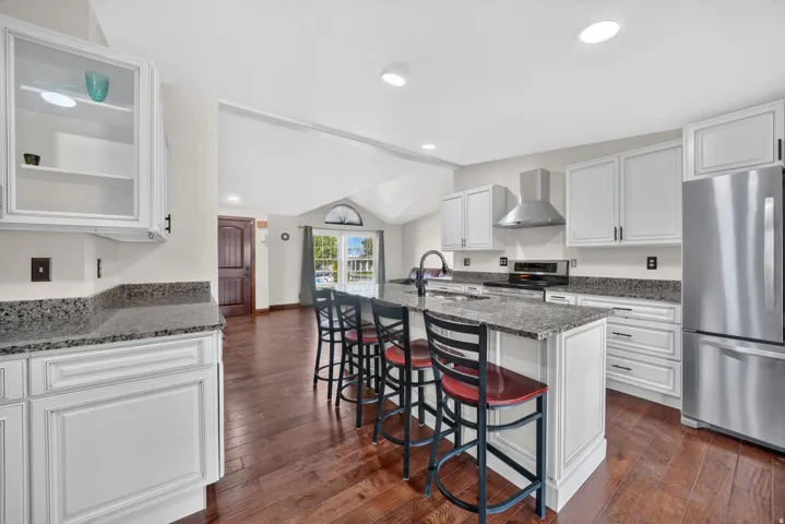 Kitchen featuring white cabinetry, stainless steel appliances, a center island with seating, dark wood-finish flooring, and recessed lighting