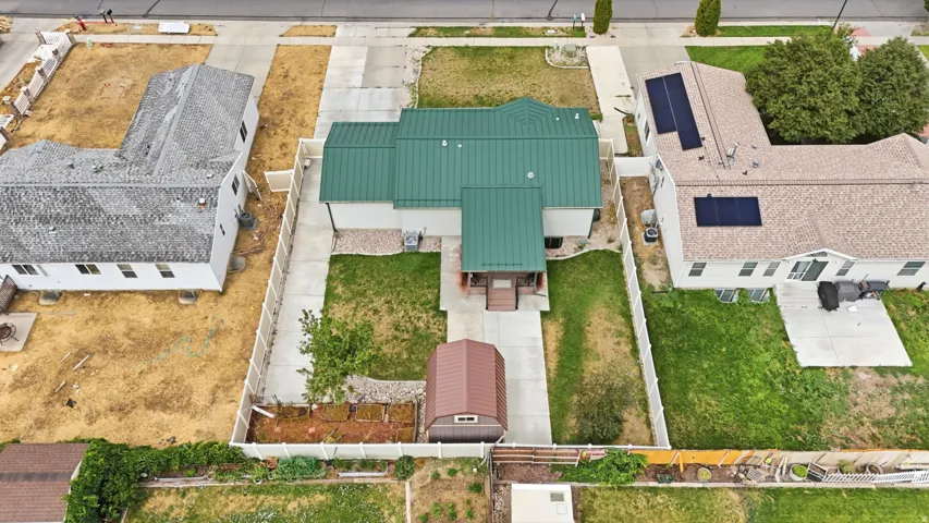 Property featuring a green metal roof, light-colored exterior siding, and a fenced perimeter