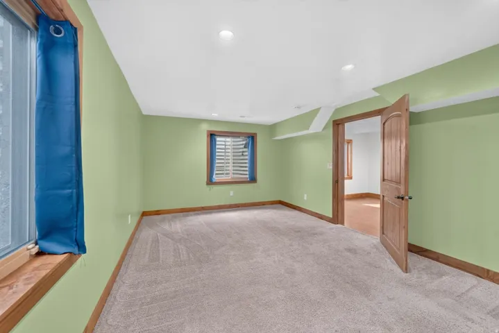 Spacious room featuring light green walls, light-colored carpeting, and recessed lighting