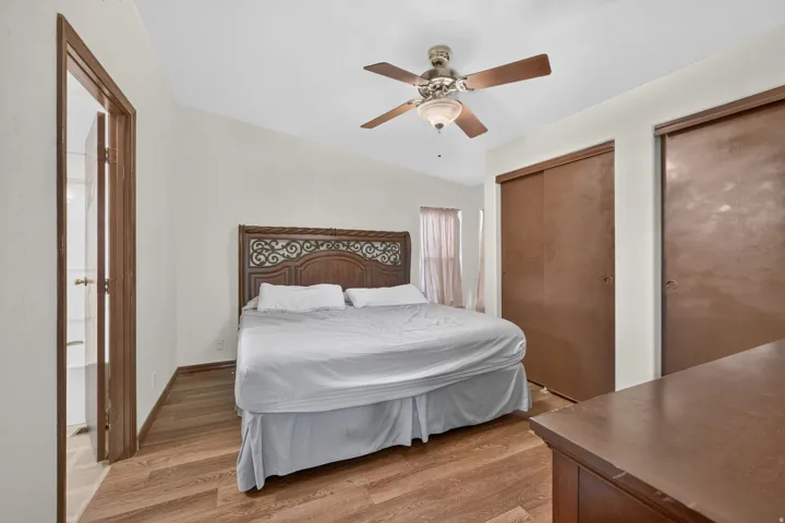 Bedroom featuring wood-finish flooring, a ceiling fan with integrated lighting, a vaulted ceiling, and sliding closet doors
