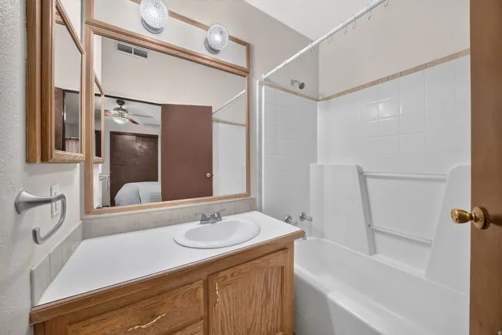 Bathroom vanity with an integrated sink, wood-finish cabinetry, and a large wall-mounted mirror