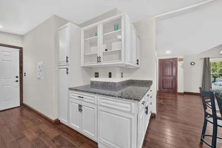 White cabinetry with black hardware, glass-front upper cabinets, and a speckled countertop