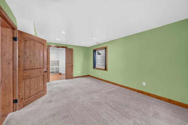 Spacious room featuring light green walls and plush gray carpeting