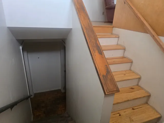 Staircase featuring wood-finish treads and risers, with a wood-finish handrail