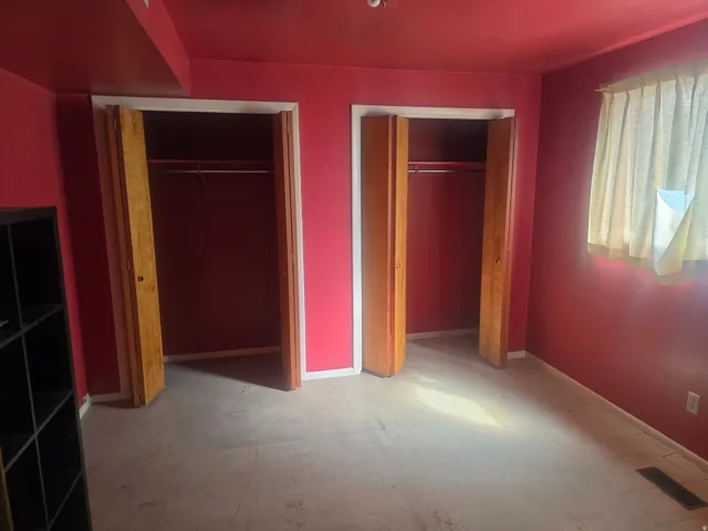 Room with two built-in closets featuring bi-fold wood doors