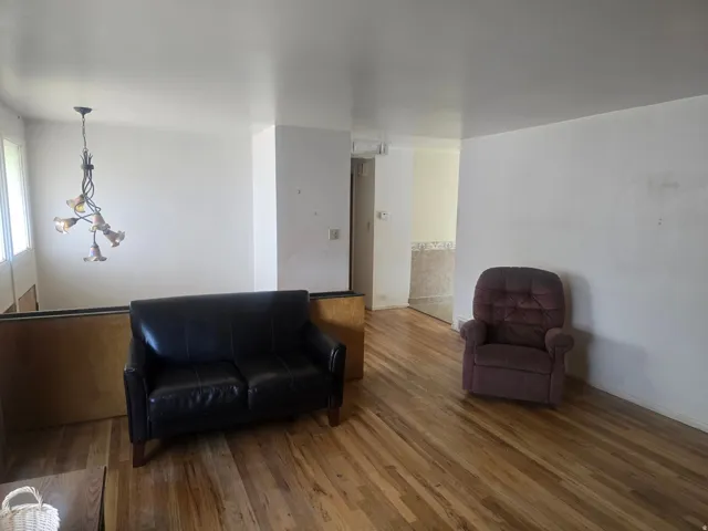 Hardwood-style flooring throughout the main living area, featuring a decorative chandelier and a half-wall partition
