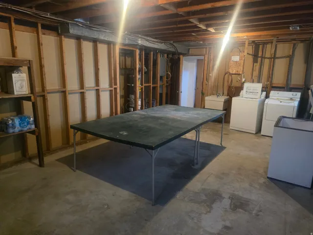 Unfinished basement featuring exposed wood framing, concrete flooring, and an exposed ceiling