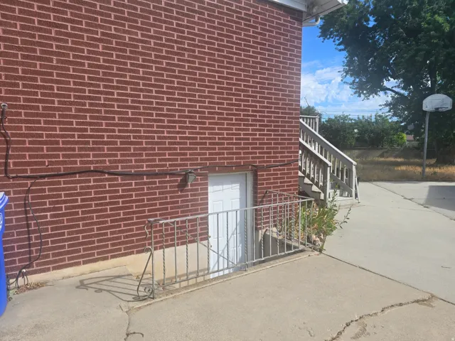 Brick exterior with a white entry door, secured by a wrought iron railing