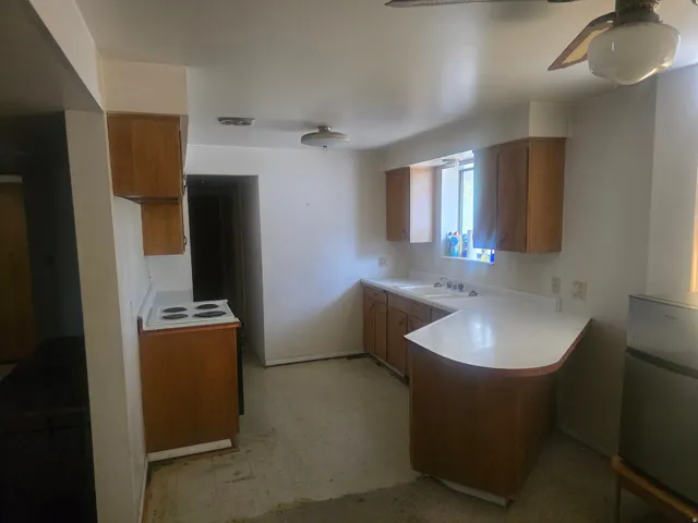 Kitchen featuring wood-finish cabinetry, white countertops, and a built-in double basin sink