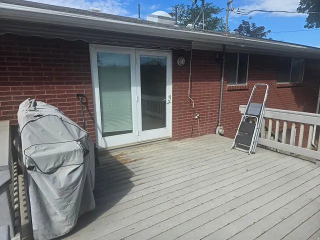 Exterior deck featuring red brick siding and white French doors