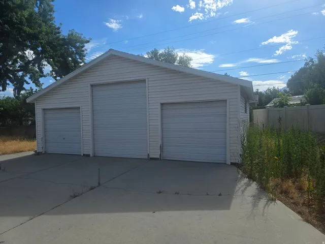 Detached three-car garage featuring white vinyl siding and a concrete driveway