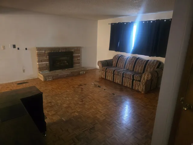Living area featuring a brick fireplace with a raised hearth, parquet flooring, and a window opening