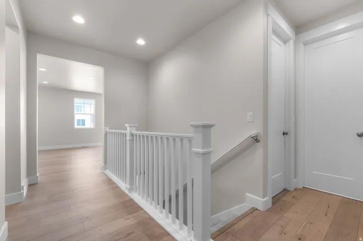Hallway with light wood-finish flooring, recessed lighting, and white baseboards