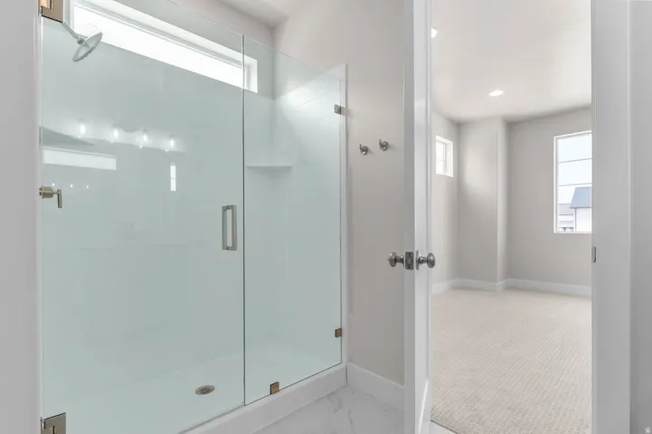 Glass-enclosed shower with brushed nickel hardware, integrated shelving, and transom window