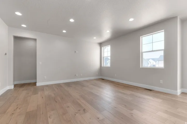 Spacious room featuring wood-finish flooring, recessed ceiling lighting, and two multi-pane windows