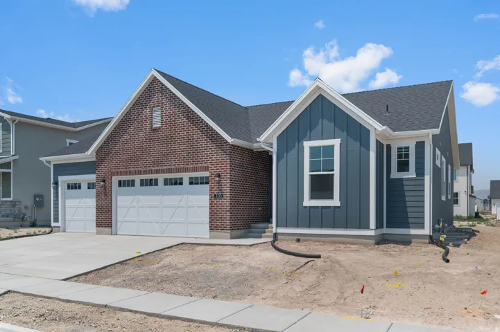 Modern facade combining red brick and blue vertical and horizontal siding, featuring a two-car garage with white paneled doors, white trim, and a dark shingled roof
