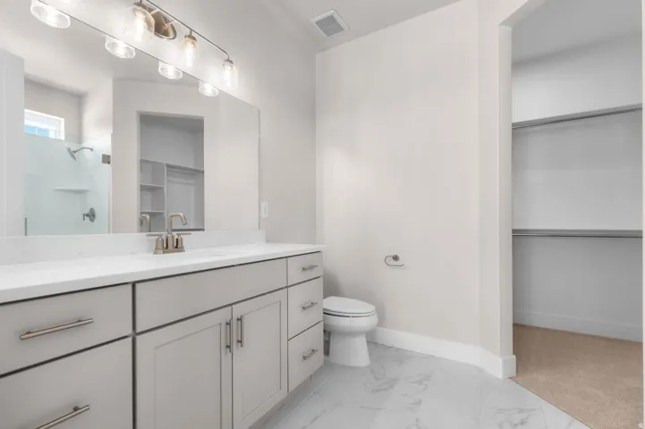 Bathroom featuring a double vanity with light gray cabinetry, brushed nickel hardware, and a white countertop
