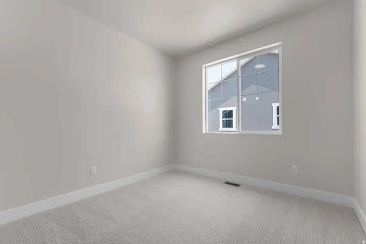 Neutral-toned room featuring a large window, light gray carpeting, and white baseboards