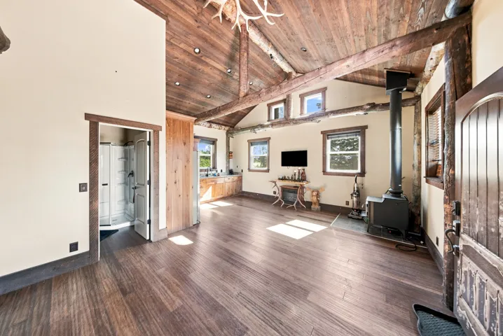 Vaulted wood-plank ceilings with exposed beams, wood-finish flooring, and multiple windows