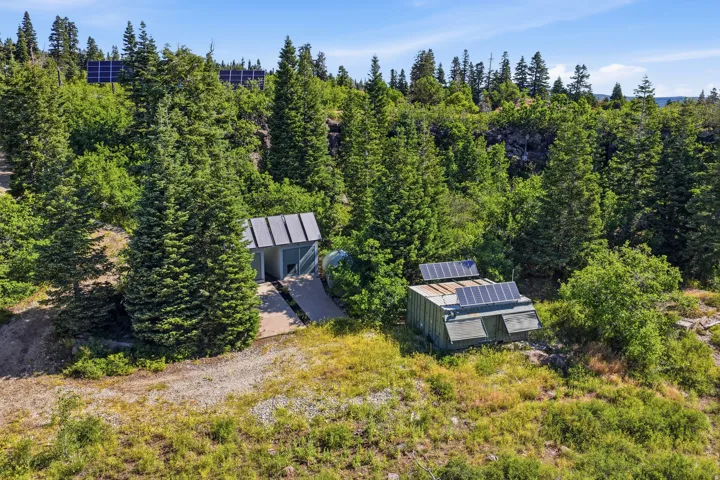 Wooded hillside property featuring two structures with integrated solar panels