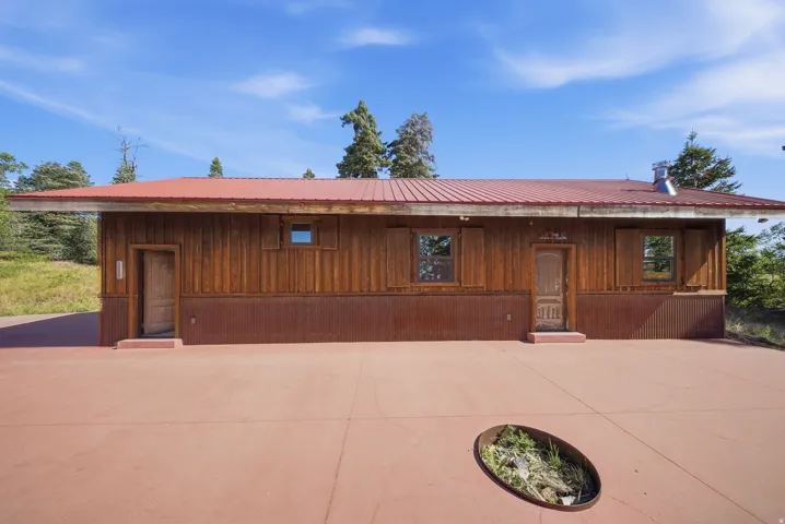 Rustic wood-paneled exterior with a red metal roof and corrugated metal wainscoting