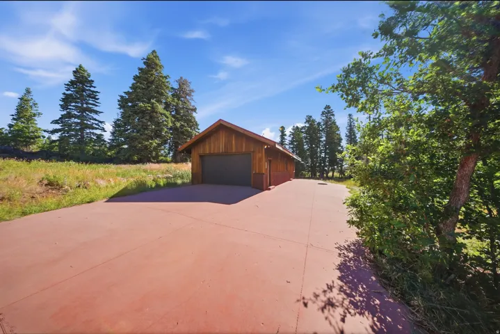 Garage structure featuring wood siding and a dark garage door
