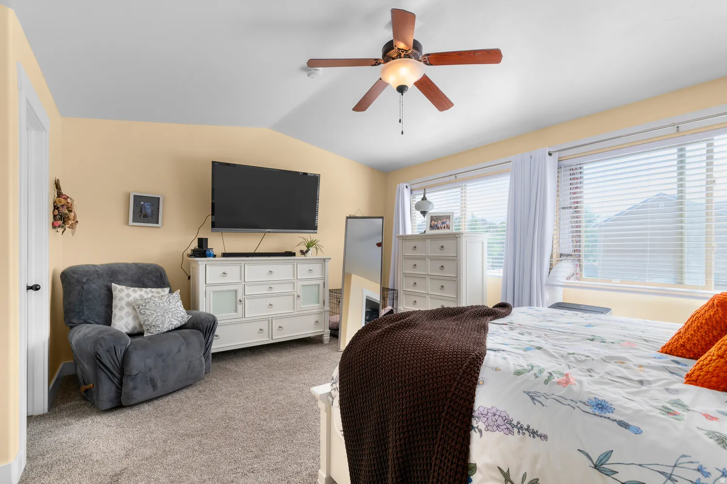 Carpeted room featuring multiple windows with blinds, a ceiling fan, and painted walls