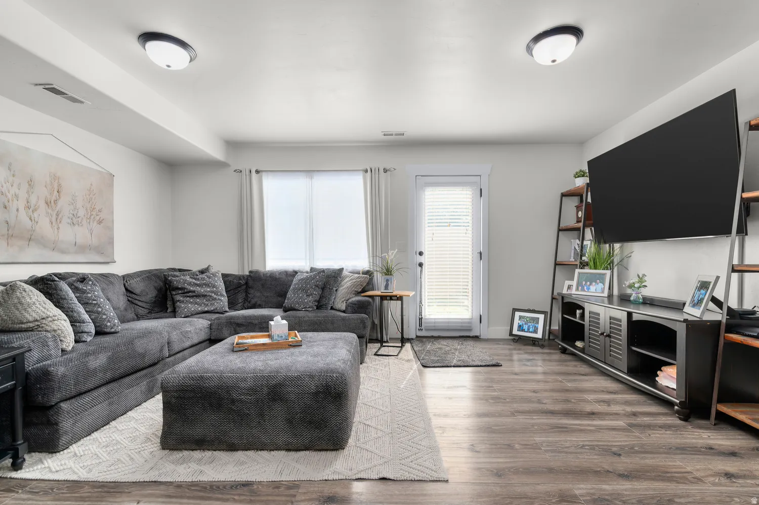 Spacious living area featuring wood-finish flooring and light-toned walls