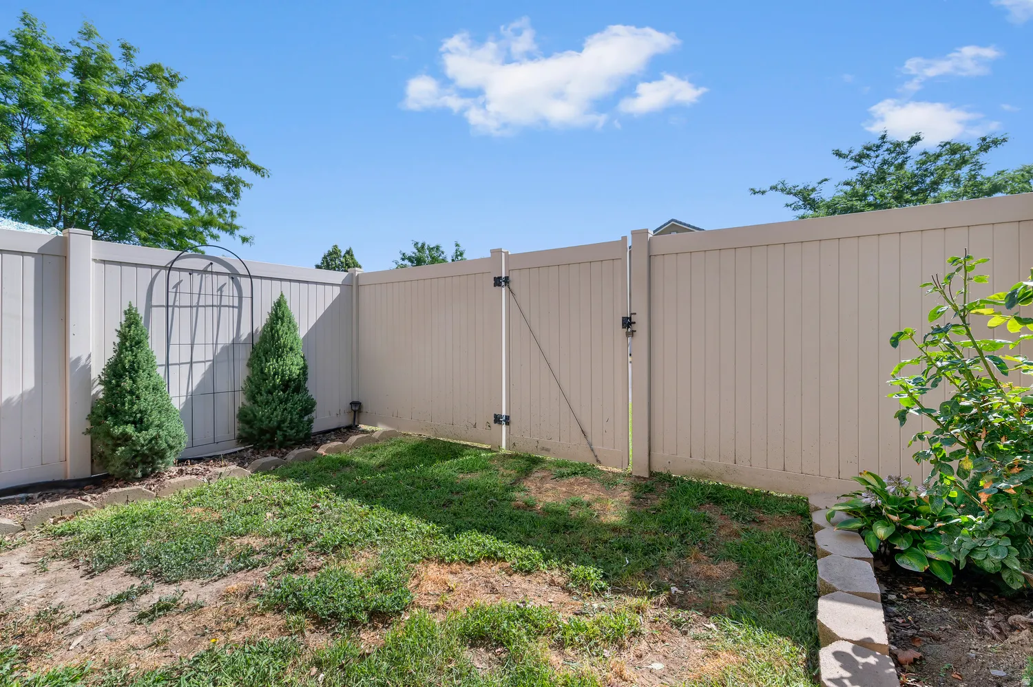 Private backyard area featuring a full-height privacy fence, a privacy fence gate, and a manicured planting bed