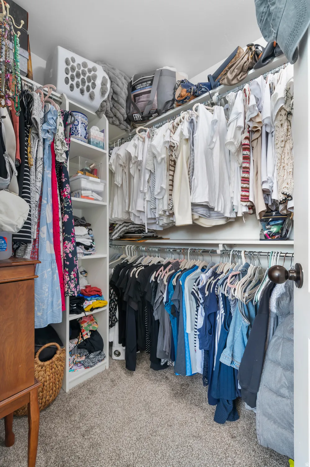 Built-in closet system featuring white shelving, multiple hanging rods, and an integrated corner unit