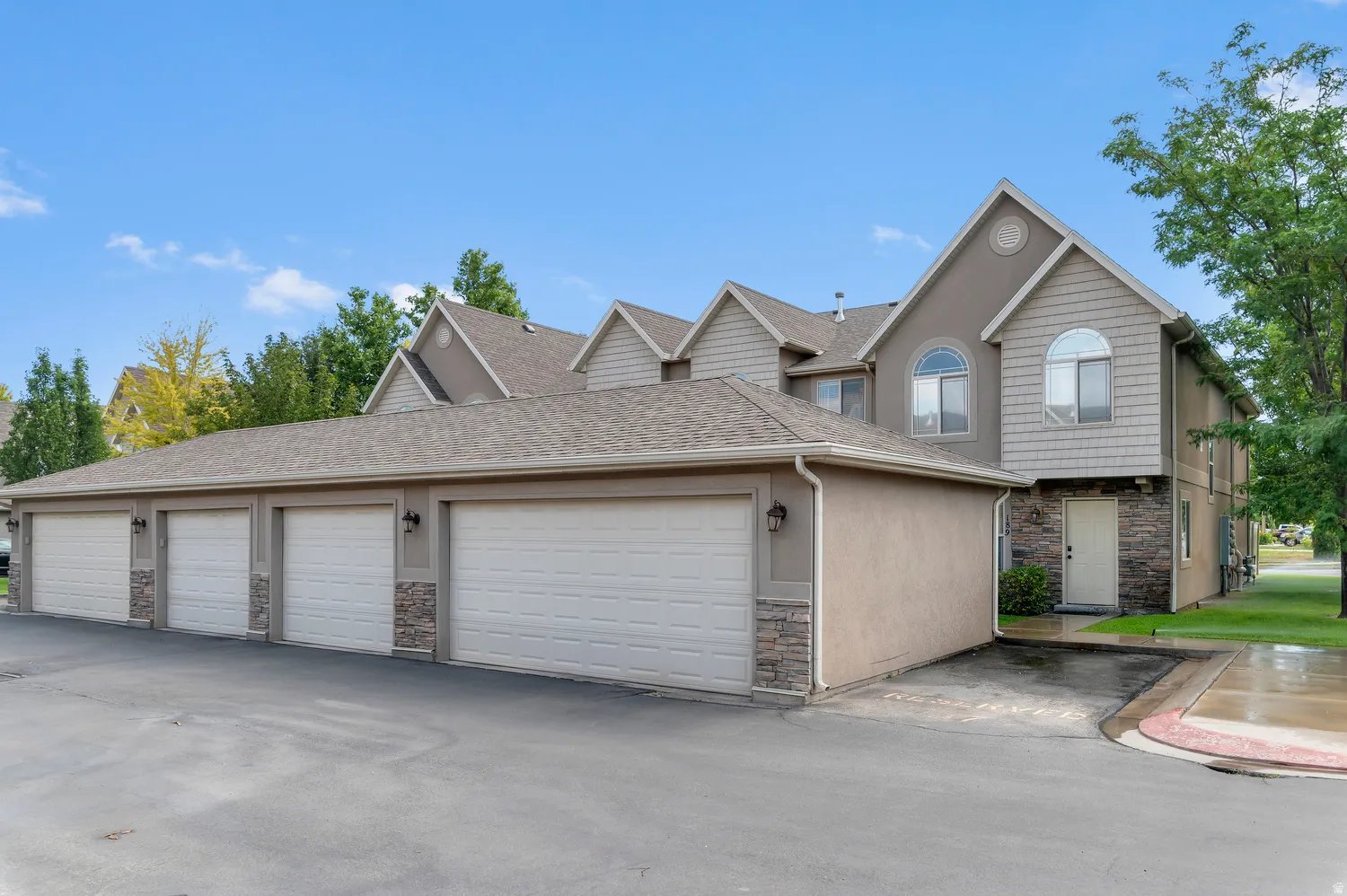 Multi-unit residential structure featuring attached garages, stucco siding, and stone accents